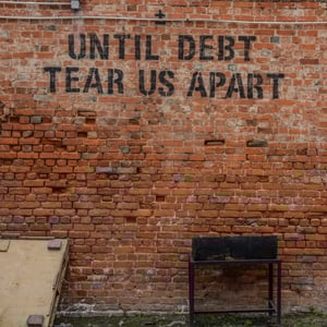 Brick wall, exterior, with stencilled black spray paint reading: 