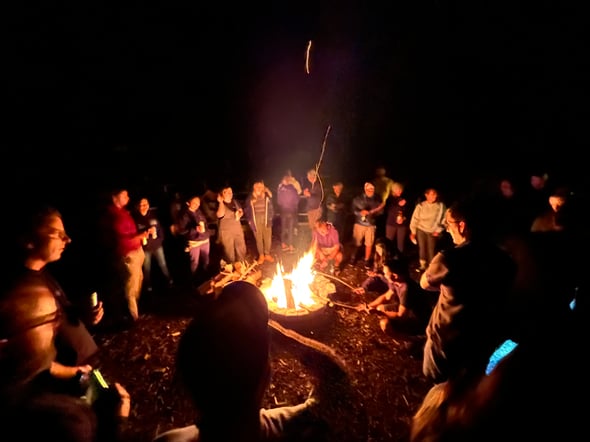 A photo of the ZayZoon team roasting marshmallows over a fire at night during summer camp.